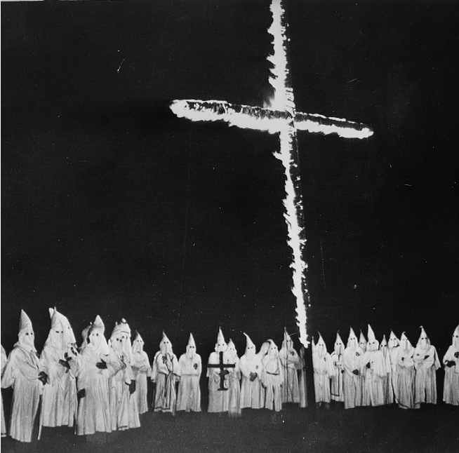 A large group of Klansman gathering to do a cross burning.