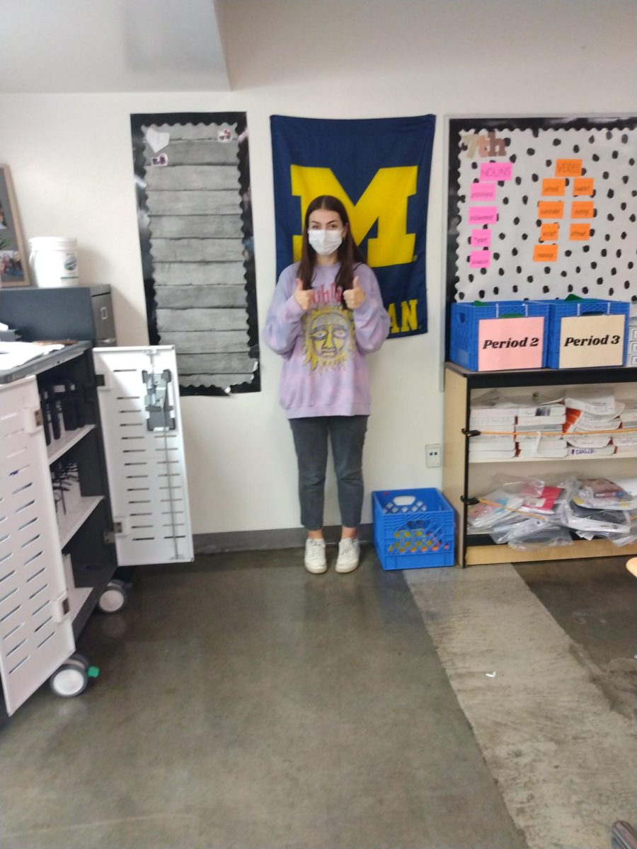 Ms. Brede in front of the University of Michigan flag in her classroom.