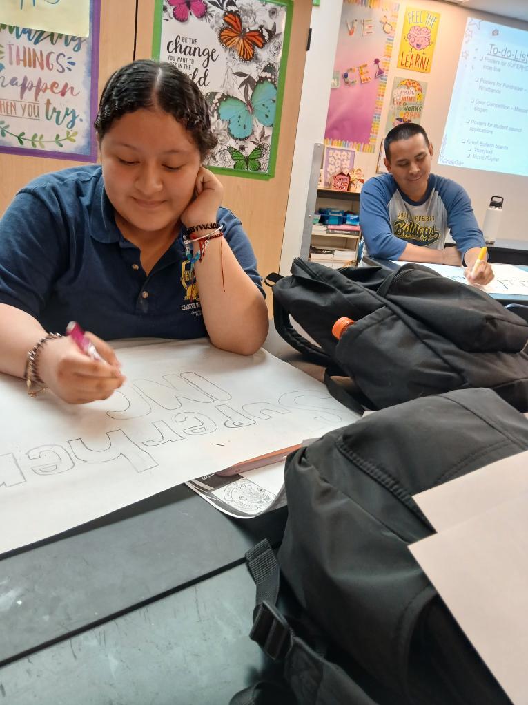 She is working on a poster for the superhero incentive alongside Mr. Aleman. 