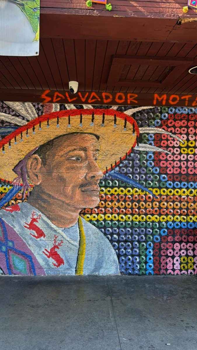 This is a painting of a Huichol outside of a restaurant.