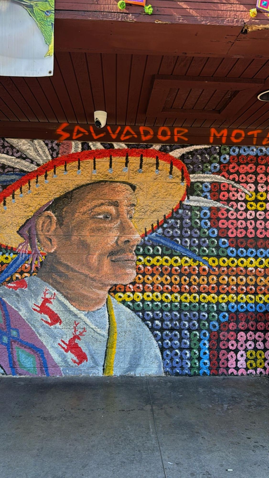 This is a painting of a Huichol outside of a restaurant.