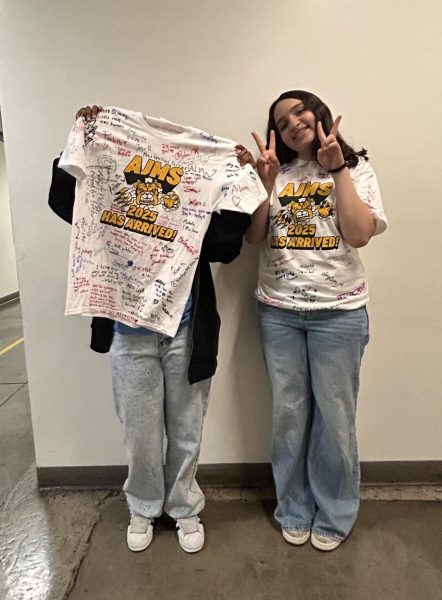 Xathzire and Jay'Onna taking a picture with their eighth grade shirts in the hallway.