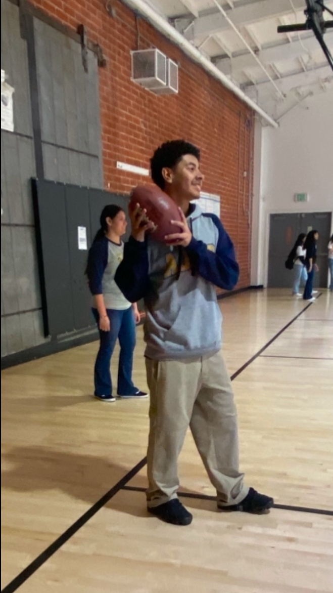 Carlos playing football in the school gym.