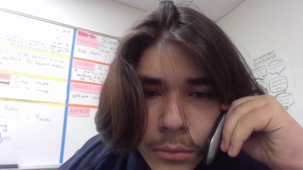 Gerardo faking a phone call with a flip phone.