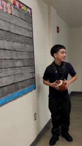 Jayden is holding a football in the hallway.