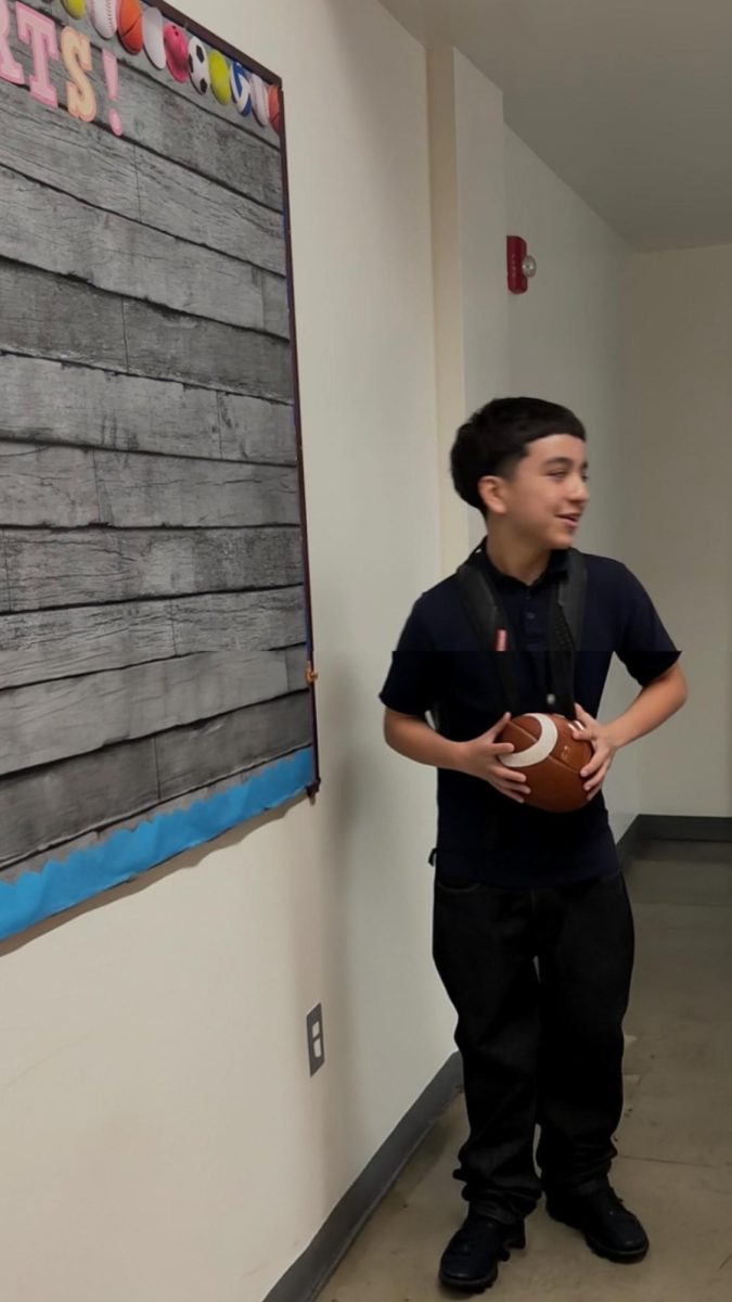 Jayden is holding a football in the hallway.