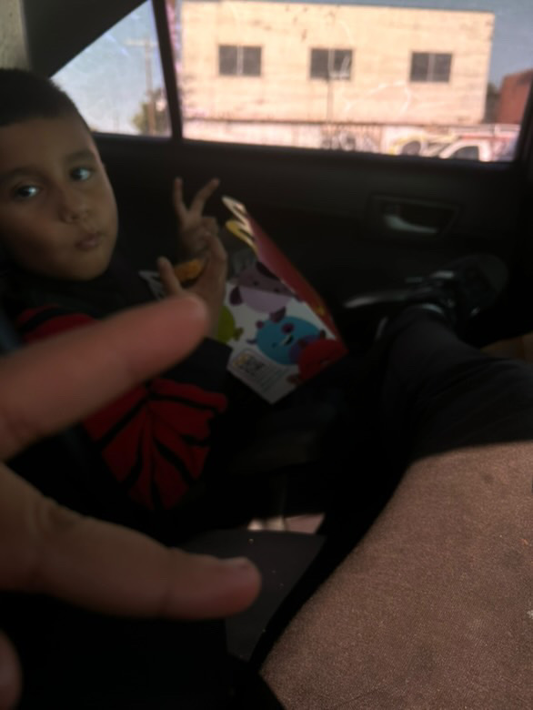 Elizabeth takes a picture of Eli in their family car.