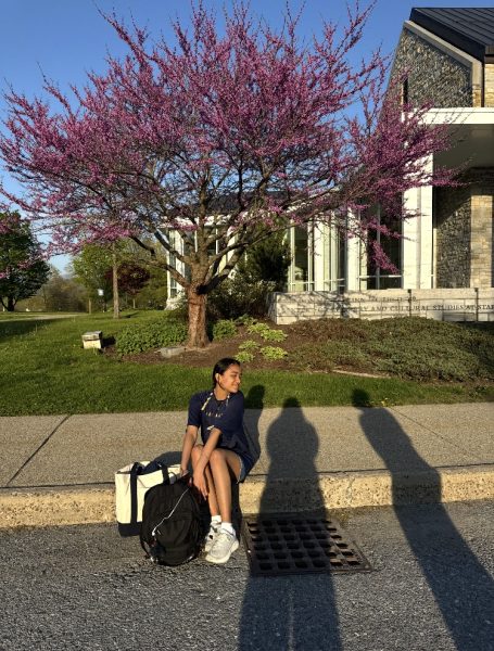 Endina sits down on the sidewalk while her friend takes a picture of her.