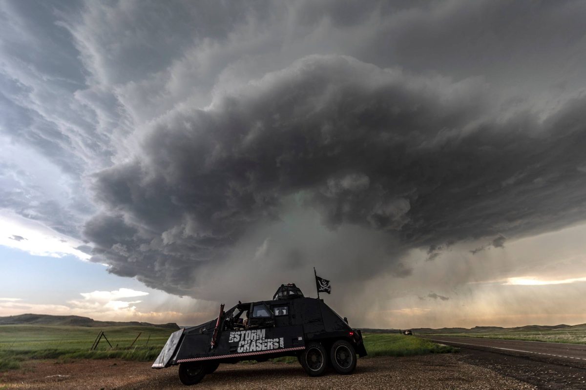 A tornado forming and a tornado chaser's car moving from the tornado.