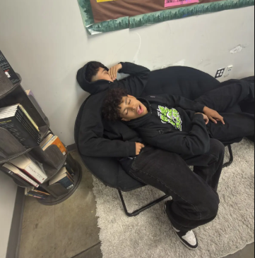 Brandon is laying down on top of Guilmar in Mr. Finer's class.
